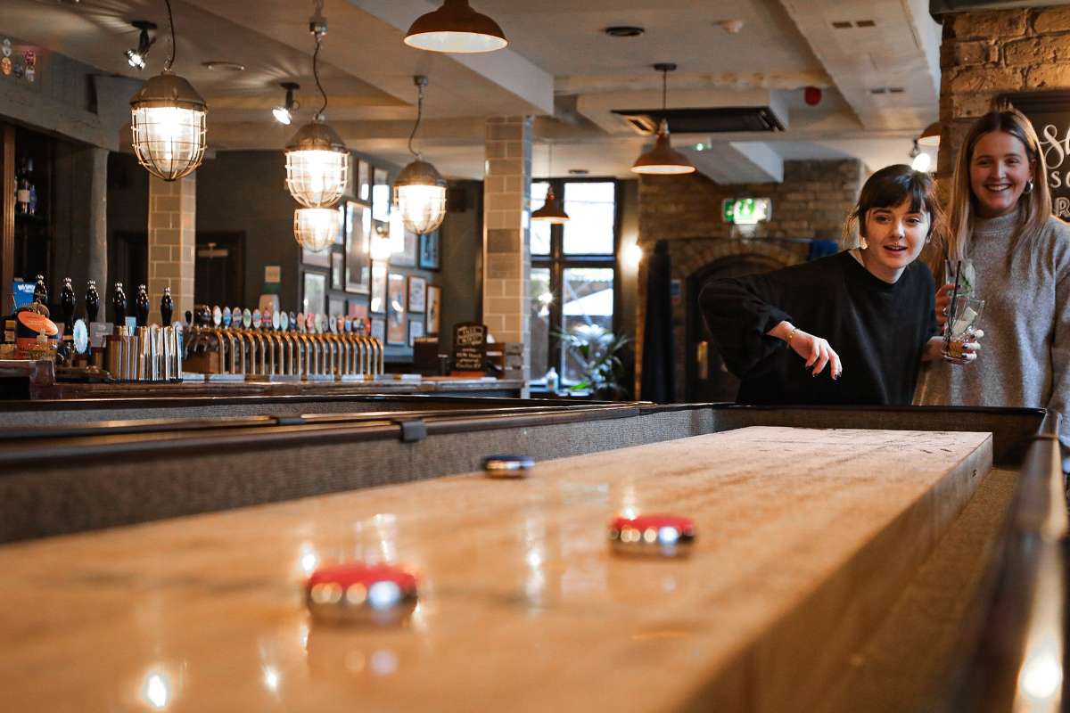 people-playing-shuffleboard-at-the-prince-of-wales-townhouse-in-the-daytime