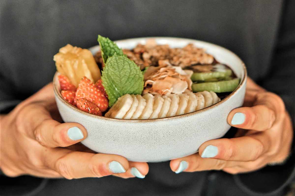 hands-holding-bowl-topped-with-fruit-and-granola-from-café-janis