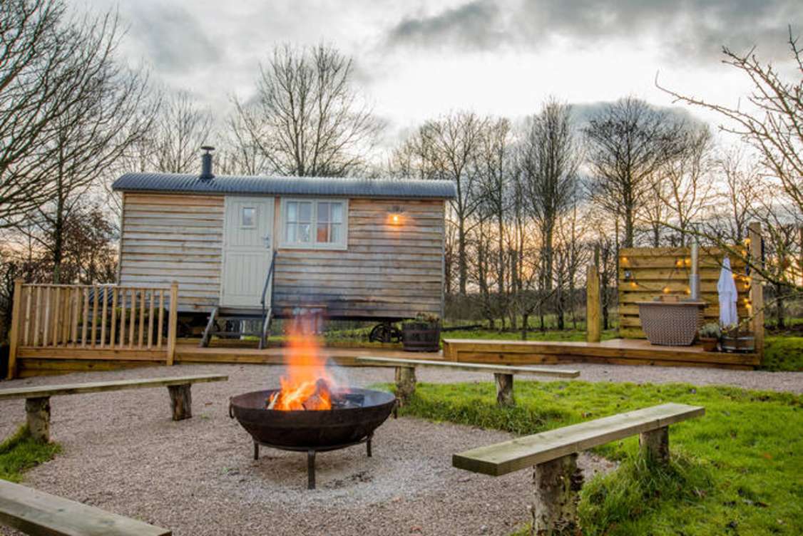 exterior-of-meadow-view-orchard-hut-with-lit-fire-pit-in-the-evening