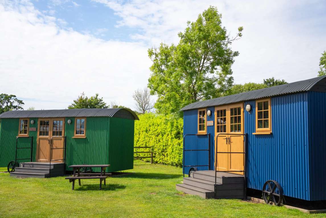 exterior-of-two-huts-at-lytchett-manor-shepherd's-huts-in-the-daytime